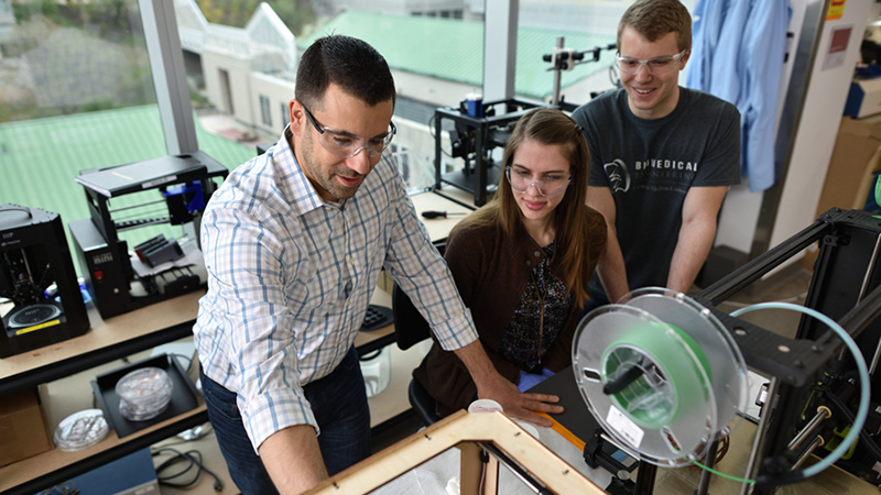 students working with faculty member in lab