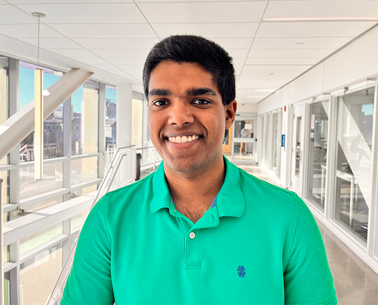 A young man smiles in a bright hallway.